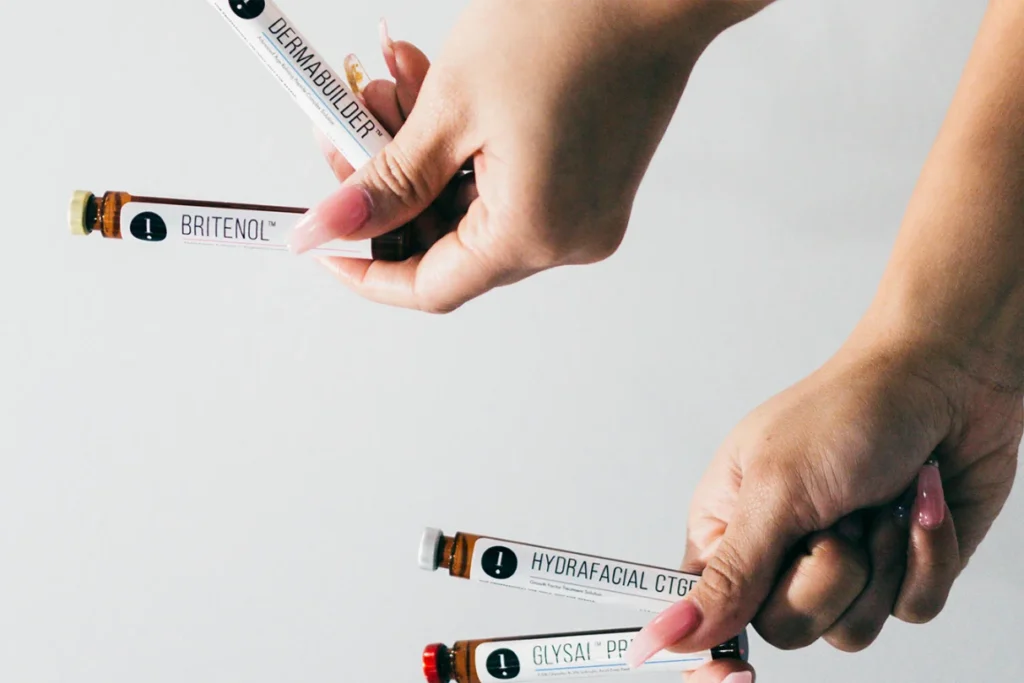 Two hands holding vials with Britenol and other skin oils.